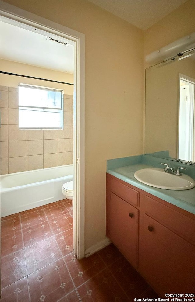 full bathroom featuring vanity, tiled shower / bath, and toilet