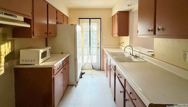 kitchen with white appliances, ventilation hood, sink, and a textured ceiling