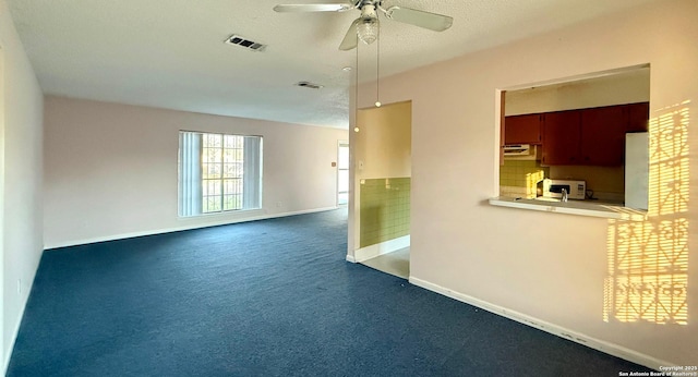 unfurnished room with ceiling fan, a textured ceiling, and dark colored carpet