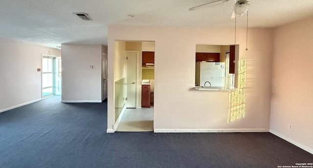 carpeted empty room featuring ceiling fan and a textured ceiling