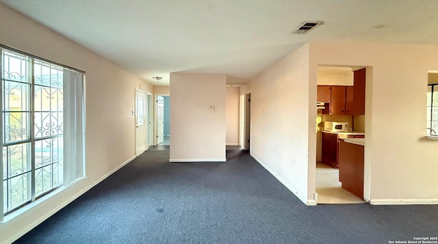 unfurnished room with a wealth of natural light and dark carpet