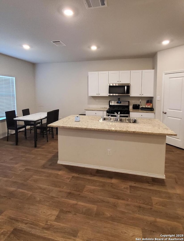 kitchen featuring dark hardwood / wood-style floors, an island with sink, white cabinets, and appliances with stainless steel finishes