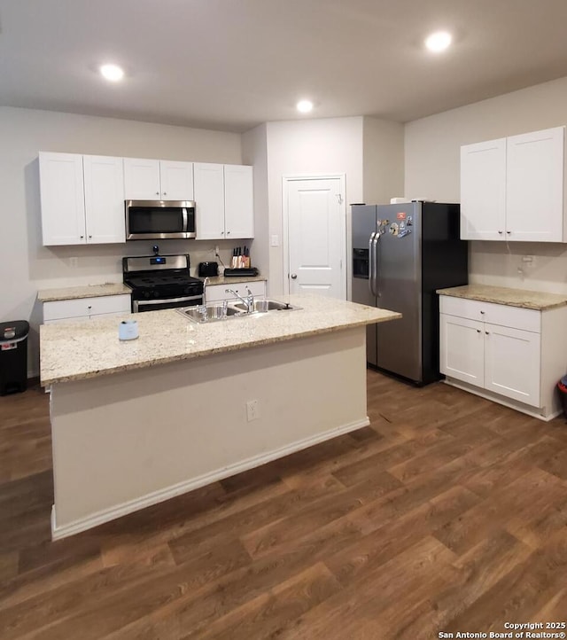 kitchen featuring stainless steel appliances, white cabinetry, dark hardwood / wood-style floors, and a center island with sink