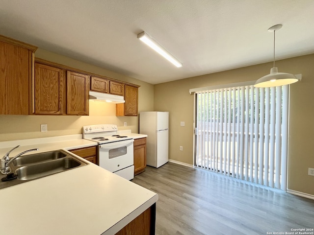 kitchen with white appliances, decorative light fixtures, light hardwood / wood-style floors, and sink