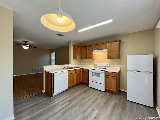 kitchen featuring sink, white appliances, hanging light fixtures, light hardwood / wood-style floors, and kitchen peninsula