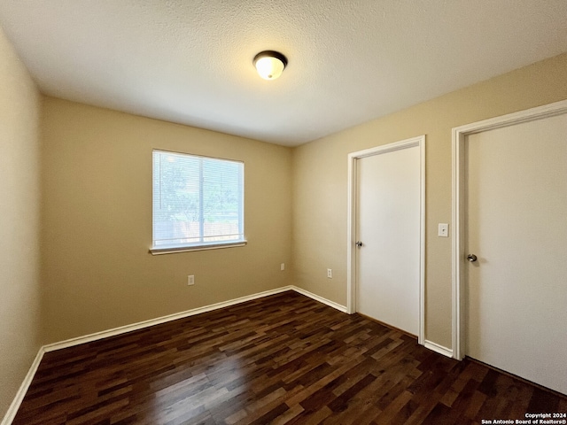 unfurnished bedroom with dark hardwood / wood-style flooring and a textured ceiling