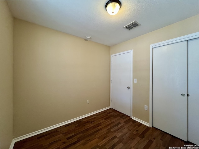 unfurnished bedroom featuring dark hardwood / wood-style flooring and a closet