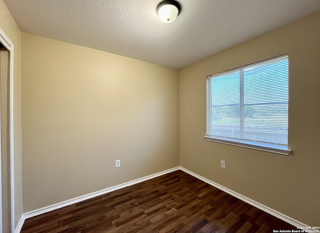 unfurnished room with dark hardwood / wood-style floors and a textured ceiling