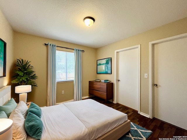 bedroom featuring dark hardwood / wood-style flooring and a textured ceiling