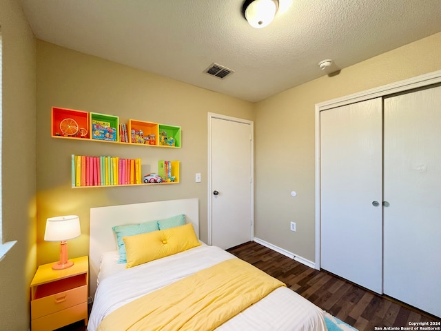 bedroom with dark hardwood / wood-style floors, a textured ceiling, and a closet