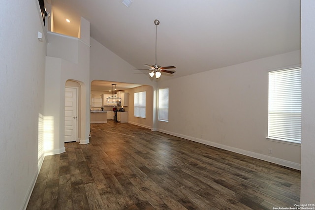 unfurnished living room featuring a healthy amount of sunlight, high vaulted ceiling, dark hardwood / wood-style floors, and ceiling fan