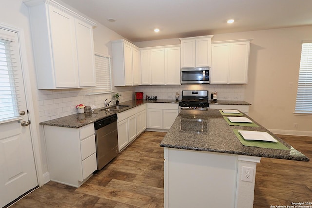 kitchen featuring white cabinetry, stainless steel appliances, a kitchen island, and dark stone countertops