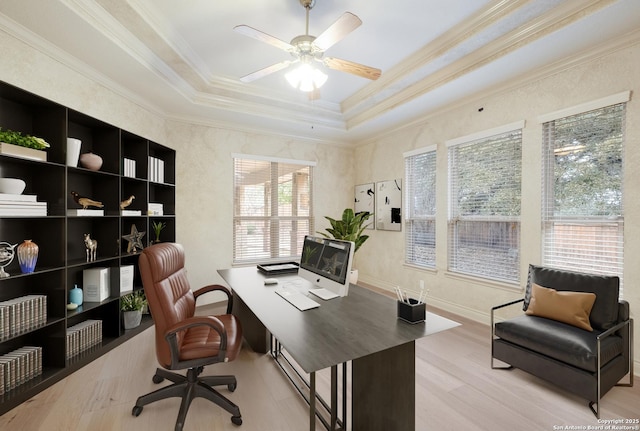 office space featuring a tray ceiling, ornamental molding, ceiling fan, and light wood-type flooring