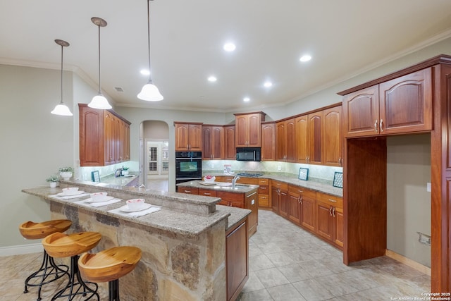 kitchen with kitchen peninsula, a kitchen bar, hanging light fixtures, light stone counters, and black appliances