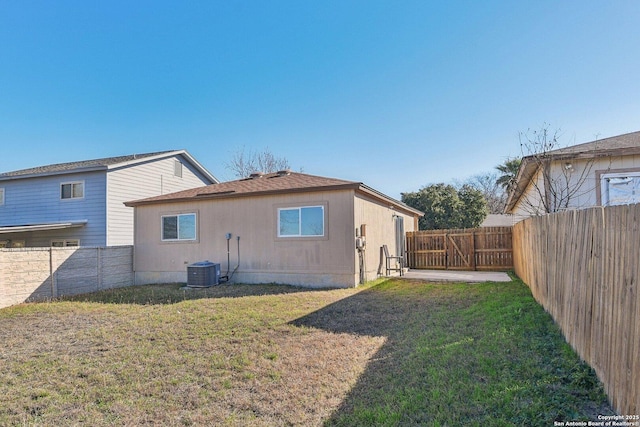 rear view of property featuring a yard and central air condition unit