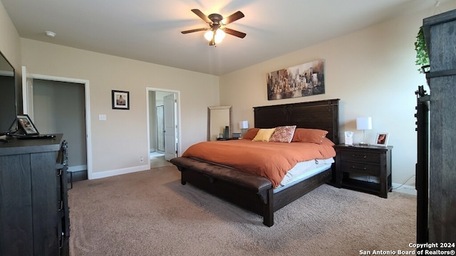 bedroom with ensuite bathroom, light colored carpet, and ceiling fan