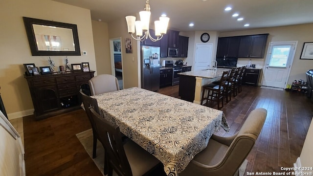 dining space featuring dark wood-type flooring, sink, and a notable chandelier