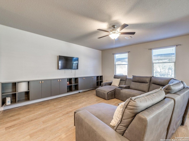 living room featuring ceiling fan, a textured ceiling, and light wood-type flooring