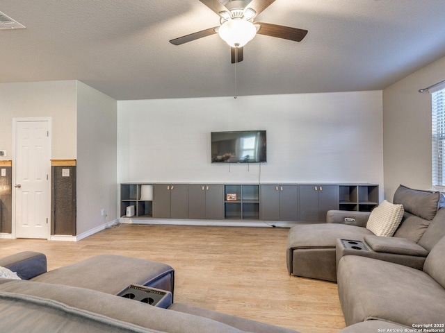 living room with ceiling fan, light hardwood / wood-style floors, and a textured ceiling