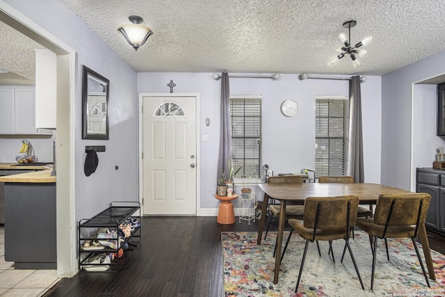 dining room with hardwood / wood-style floors, a notable chandelier, and a textured ceiling