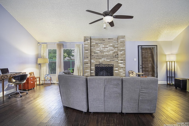 living room with a fireplace, lofted ceiling, ceiling fan, dark wood-type flooring, and a textured ceiling