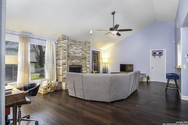 living room featuring high vaulted ceiling, a fireplace, dark hardwood / wood-style flooring, ceiling fan, and a textured ceiling