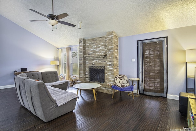 living room featuring vaulted ceiling, ceiling fan, a brick fireplace, dark wood-type flooring, and a textured ceiling