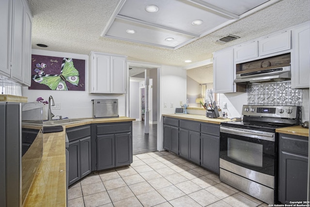 kitchen with white cabinetry, wooden counters, a textured ceiling, light tile patterned floors, and electric stove