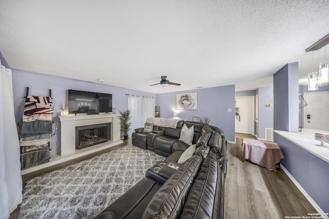 living room with ceiling fan, wood-type flooring, and a textured ceiling