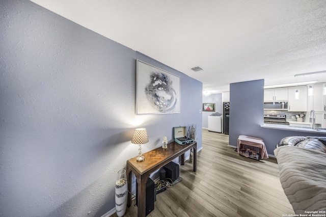 hallway with wood-type flooring and washer / dryer