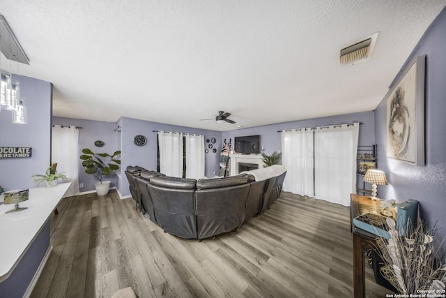 living room featuring ceiling fan, a healthy amount of sunlight, hardwood / wood-style floors, and a textured ceiling