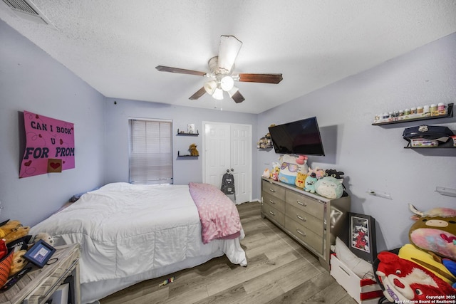 bedroom with ceiling fan, a textured ceiling, light hardwood / wood-style floors, and a closet