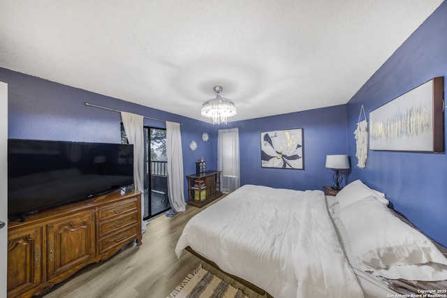 bedroom with an inviting chandelier, light hardwood / wood-style flooring, and a textured ceiling