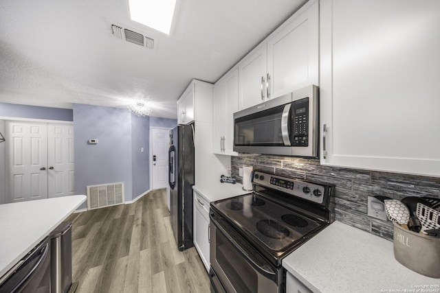 kitchen featuring tasteful backsplash, appliances with stainless steel finishes, light hardwood / wood-style flooring, and white cabinets