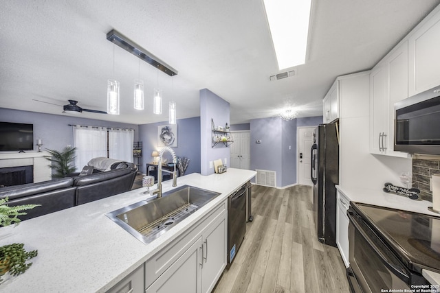 kitchen with sink, light hardwood / wood-style flooring, black appliances, white cabinets, and decorative light fixtures