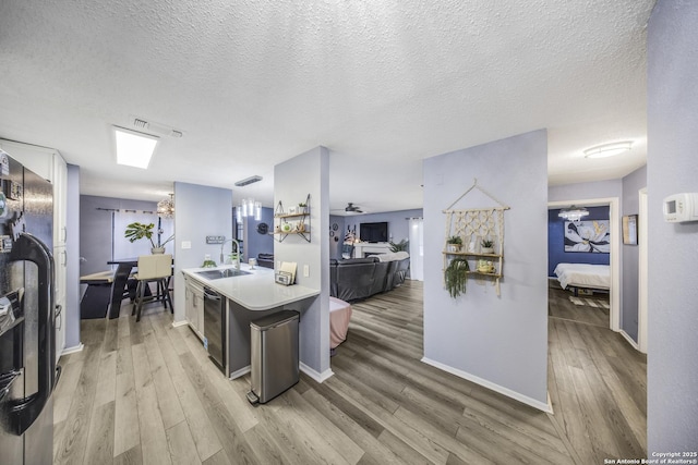 kitchen featuring sink, hardwood / wood-style floors, black appliances, a textured ceiling, and white cabinets