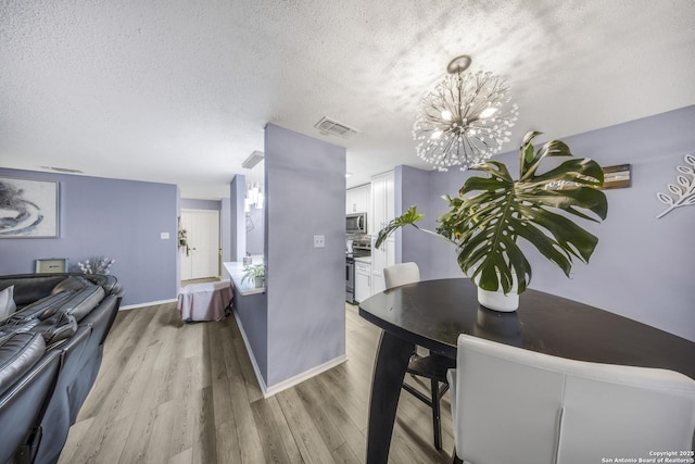 dining space with a chandelier, light hardwood / wood-style flooring, and a textured ceiling