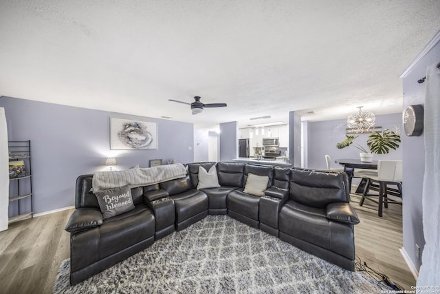 cinema room featuring ceiling fan with notable chandelier, wood-type flooring, and a textured ceiling