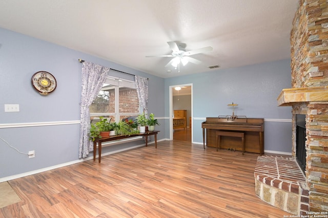 unfurnished living room with ceiling fan, a fireplace, and light hardwood / wood-style floors