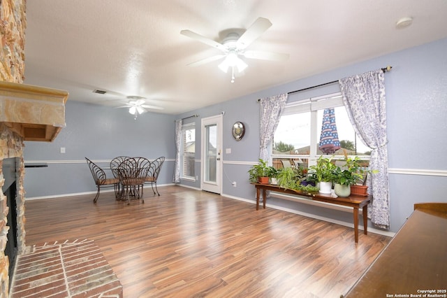 interior space with hardwood / wood-style floors, a large fireplace, and ceiling fan