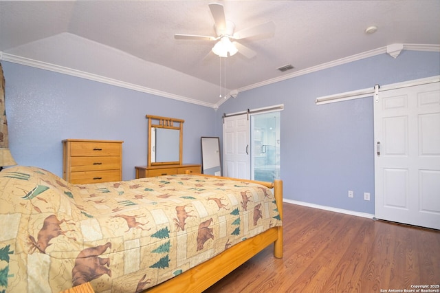 bedroom featuring dark hardwood / wood-style floors, lofted ceiling, ceiling fan, crown molding, and a barn door