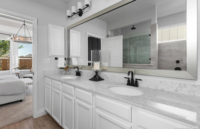 bathroom featuring hardwood / wood-style flooring, vanity, and tiled shower