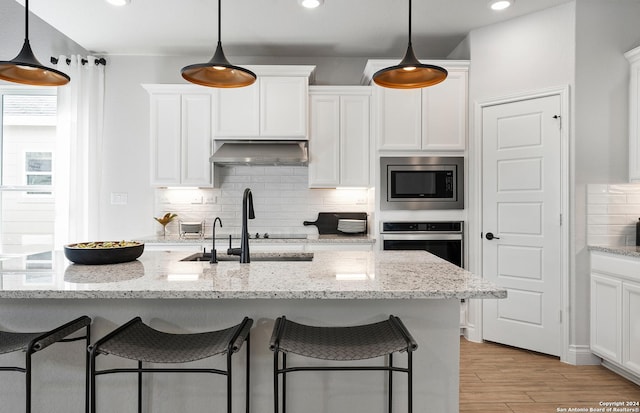 kitchen featuring stainless steel appliances, light stone countertops, sink, and white cabinets