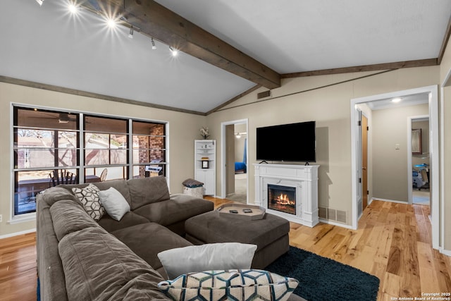 living room with lofted ceiling with beams, crown molding, and light wood-type flooring