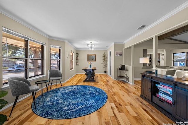 living area featuring a notable chandelier, light hardwood / wood-style flooring, and ornamental molding