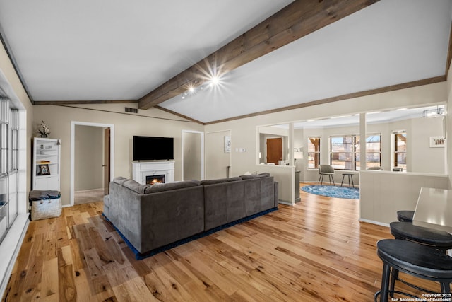 living room with crown molding, light wood-type flooring, and vaulted ceiling with beams