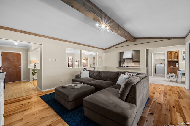 living room featuring vaulted ceiling with beams, washer / clothes dryer, crown molding, and light wood-type flooring