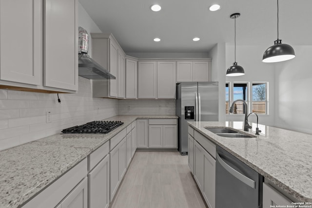 kitchen featuring tasteful backsplash, sink, hanging light fixtures, light stone counters, and stainless steel appliances