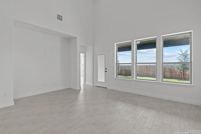 interior space featuring a towering ceiling and light hardwood / wood-style flooring