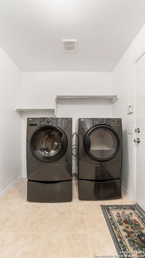 laundry area with separate washer and dryer and light tile patterned floors